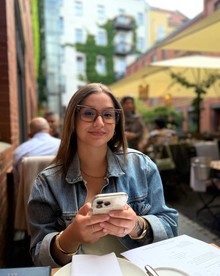 Carla checking her phone at a café terrace in Berlin